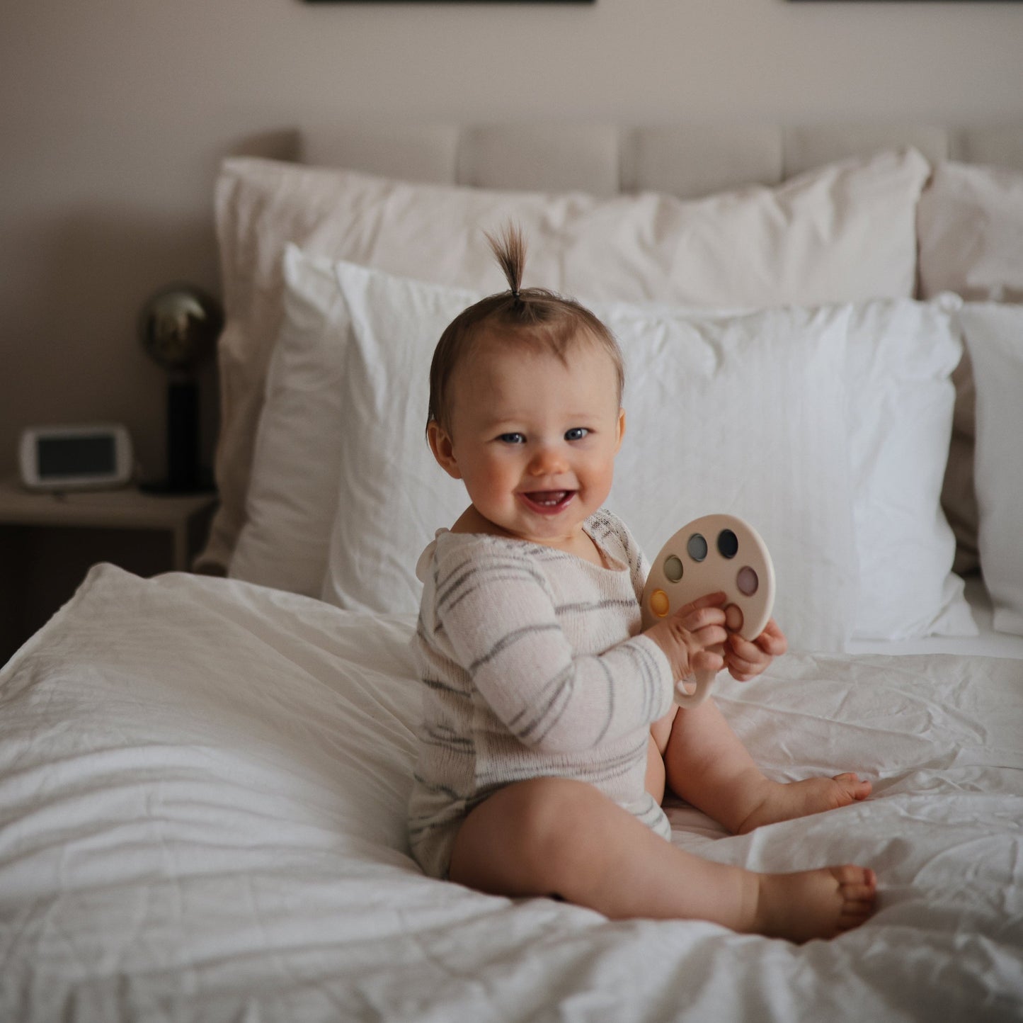 Mushie - Paint Palette Press Toy - baby on bed