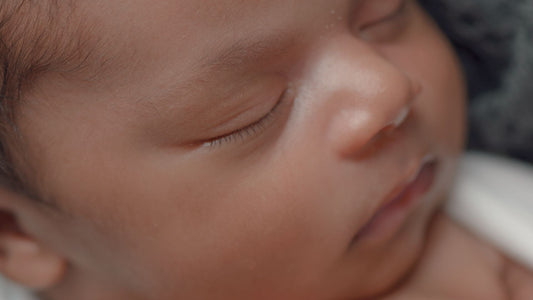 newborn baby sleeping with eyes closed and hands together