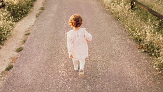 toddler walking in countryside surrounded by fields on a path