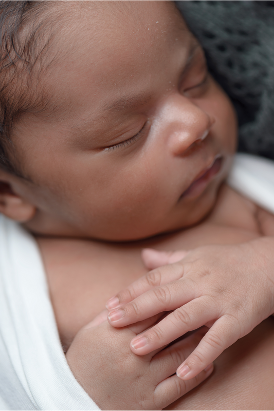 newborn baby sleeping with eyes closed and hands together