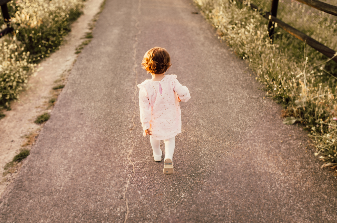 toddler walking down path in stylish clothes on a sunny day in the countryside
